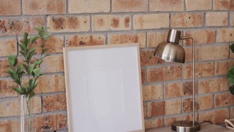 wooden frame and plant on desk with copy space against brick wall