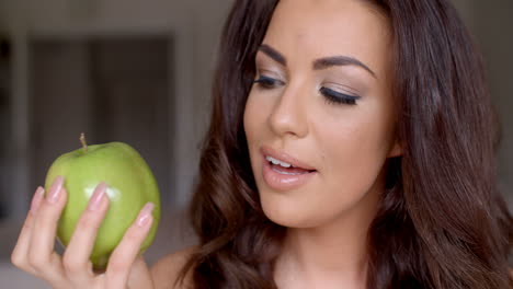 una mujer bonita sonriente sosteniendo una manzana verde fresca