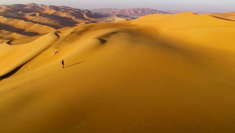 aerial view of a man walking on dunes during the sunset, u.a.e.