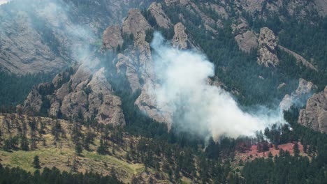 large forest fire with smoke billowing over a mountainous and forested landscape