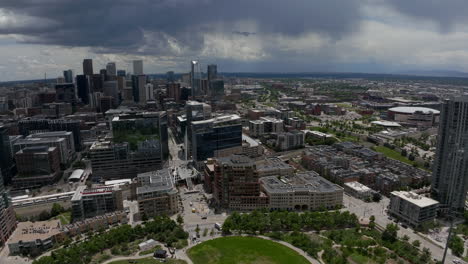 Downtown-Denver-Aerial-Drone-cinematic-REI-Ball-Arena-South-Platte-River-Elitch-Gardens-cityscape-with-foothills-Rocky-Mountain-Landscape-Colorado-cars-traffic-glass-house-summer-circling-motion