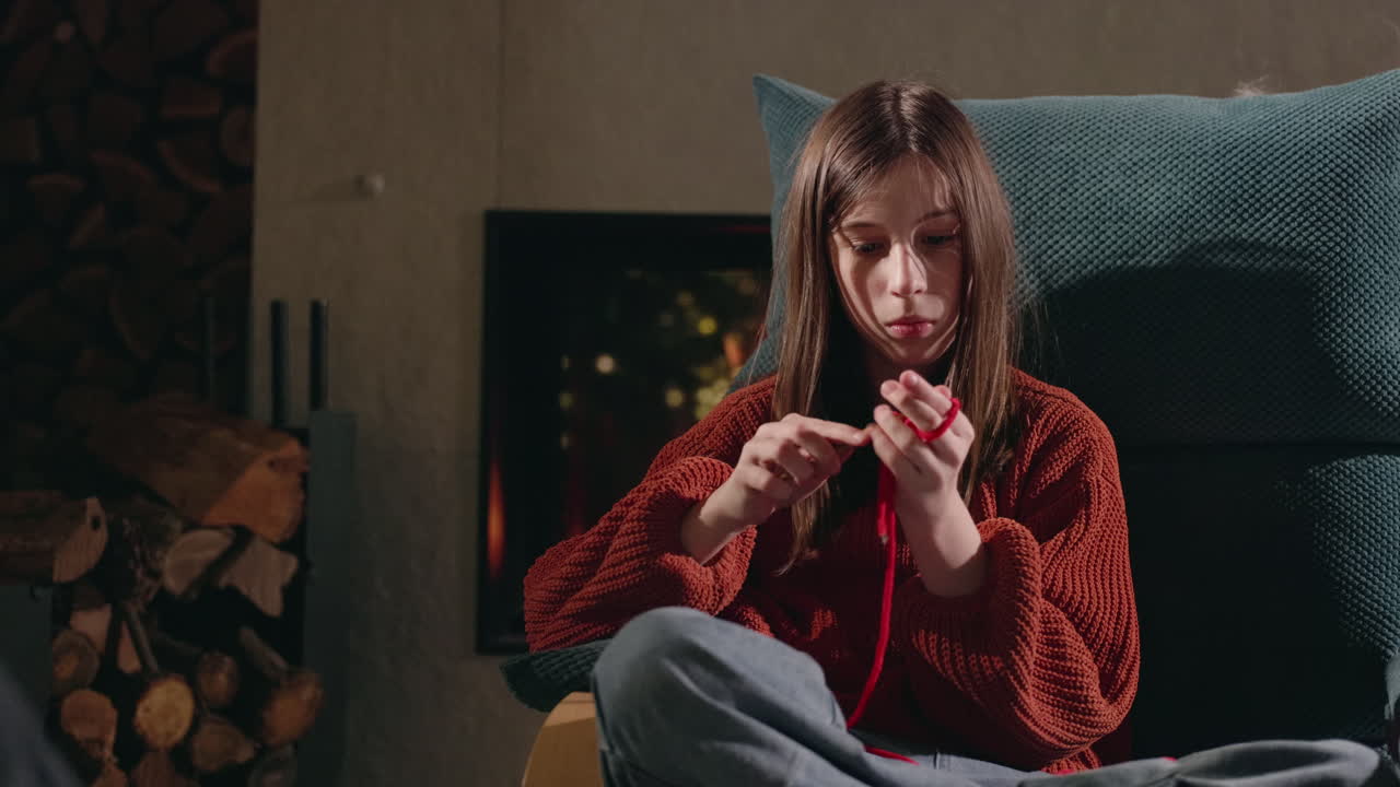 Girl Knitting in an Armchair near a Fireplace