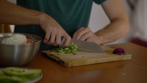 Hombre-Cortando-Cebolla-Verde-En-Una-Tabla-De-Cortar-De-Madera-En-La-Cocina-De-Casa