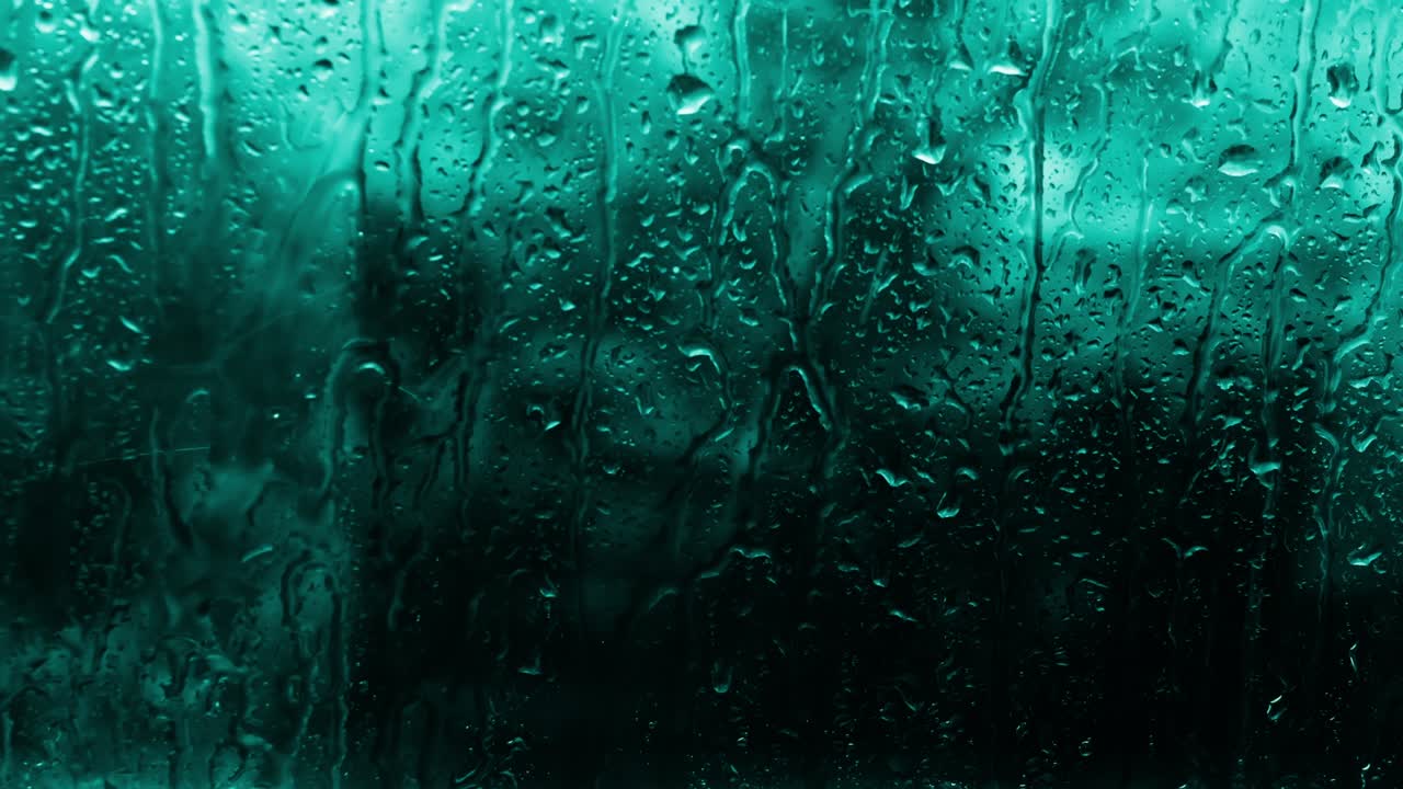 Soft focus Background of raindrops on glass in a turquoise shade of menthol. Copy space background with water drops, beautiful rain outside the window.