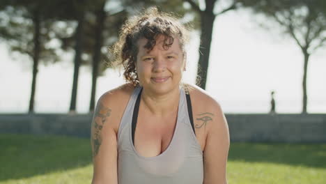 vista frontal de una mujer gorda estirándose hacia atrás y sonriendo a la cámara