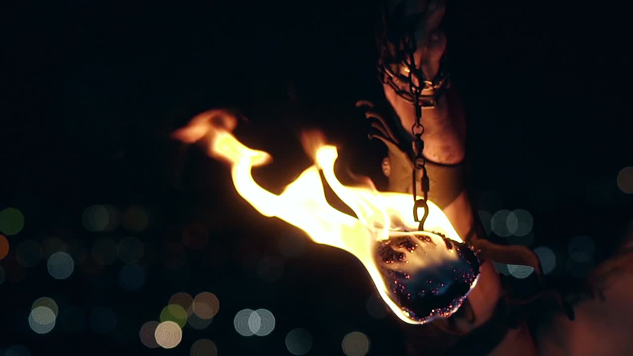 Close-up shot of burning poi hanging on chain