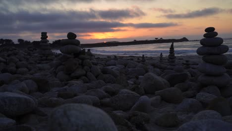 rocks stacked on top of each other with a beautiful coastal sunset in the background