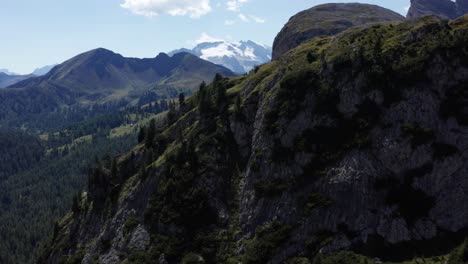 Cinematic-drone-shot-of-cliffs-by-Passo-di-Valparola,-with-Marmolada-Mountain-backdrop-in-the-Dolomites,-Italy