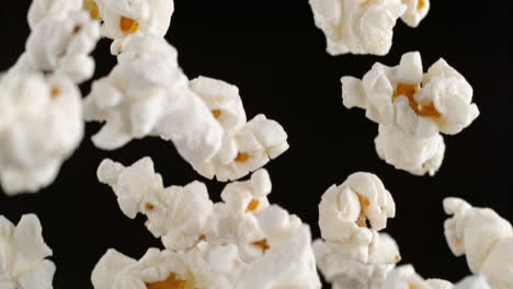 cooked popcorn kernels flying on the black background in slow motion and macro