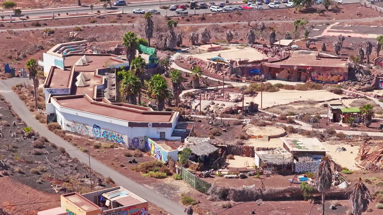 Abandoned Baku Theme Park in Corralejo: graffiti-covered structures, dry terrain, and ghosted enclosures—captured in a drone establishing shot of Fuerteventura’s forgotten leisure zone