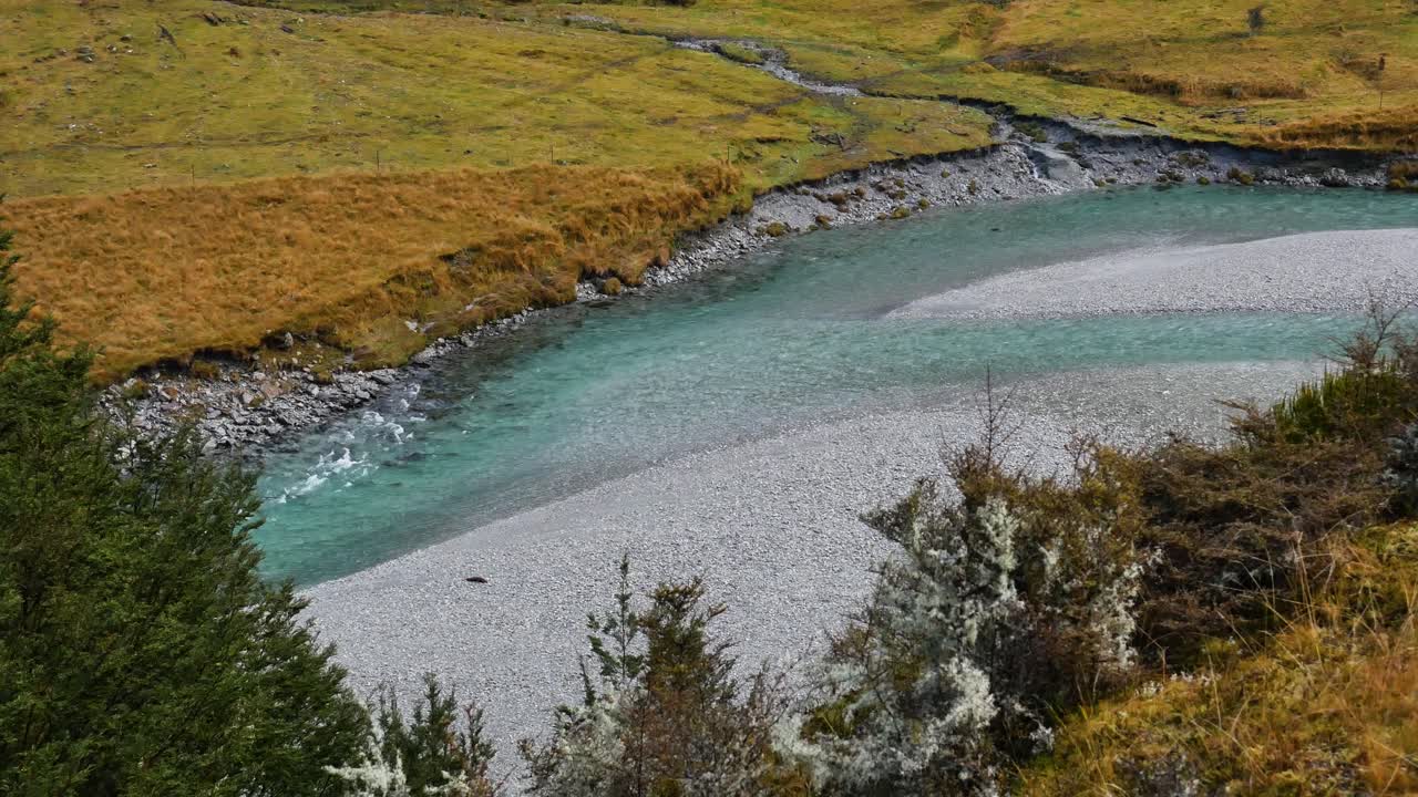 clear blue river flowing through grassy mountain valley
