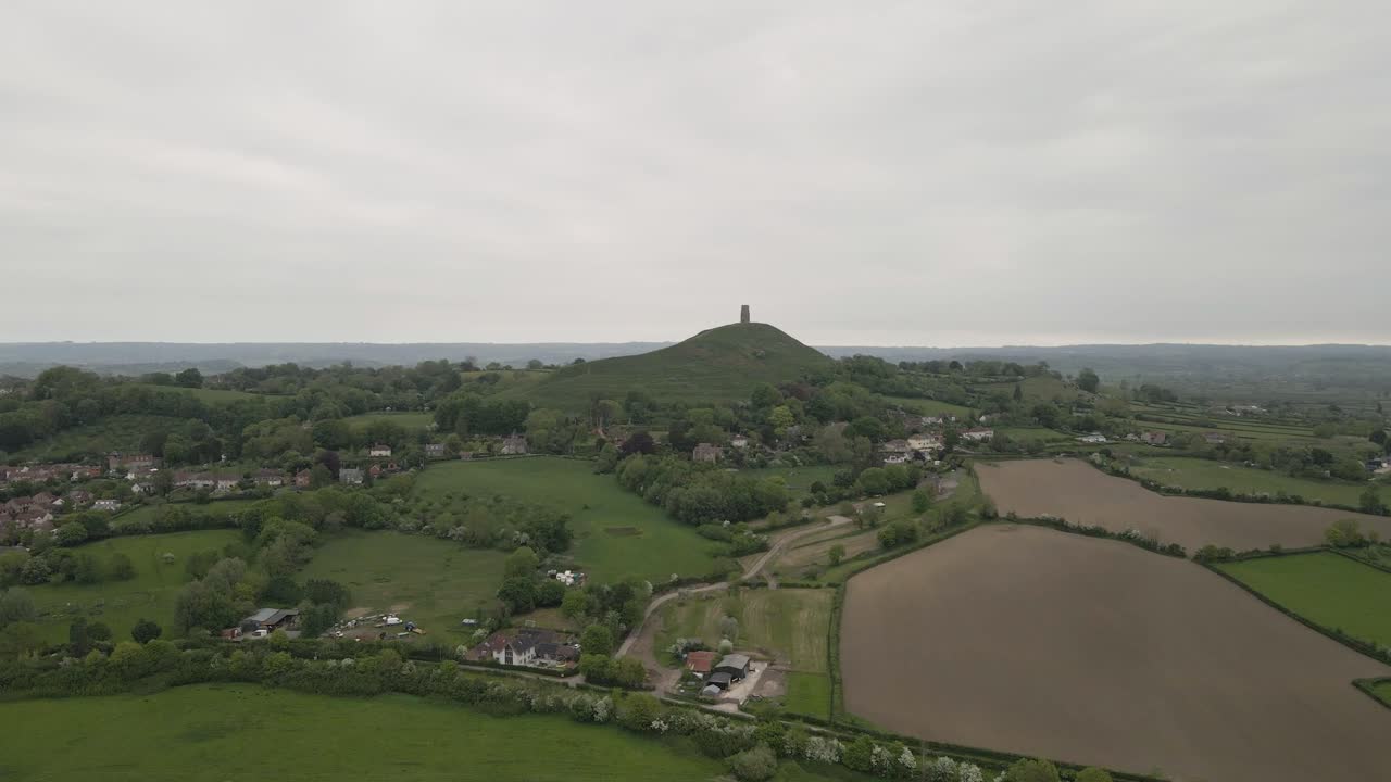 Aerial view of Glastonbury, drone moving forward to the Tor, drone flying over the green fields 4K, 60fps.