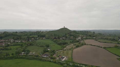 aerial view of glastonbury, drone moving forward to the tor, drone flying over the green fields 4k, 60fps.