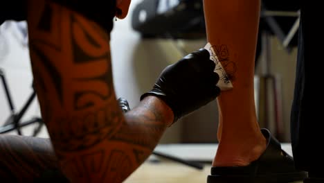 Tattoo artist removing the tracing of a dog print tattoo from a girl's twin