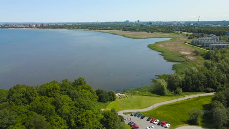 gorgeous aerial drone panning view footage of a quiet and luxurious neighborhood near baltic sea shoreline during a summer sunny day with apartment buildings and grassy areas visible where people sit.