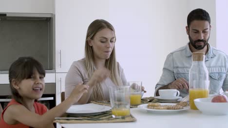 young parents and little girl having breakfast together