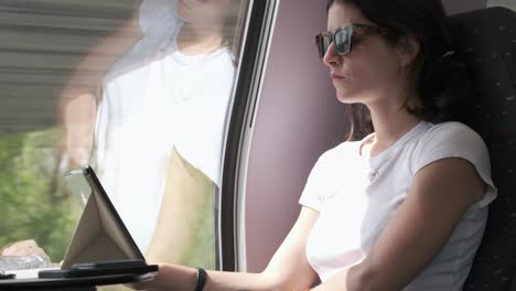 Woman-Wearing-Sunglasses-Using-Tablet-on-Train-Ride