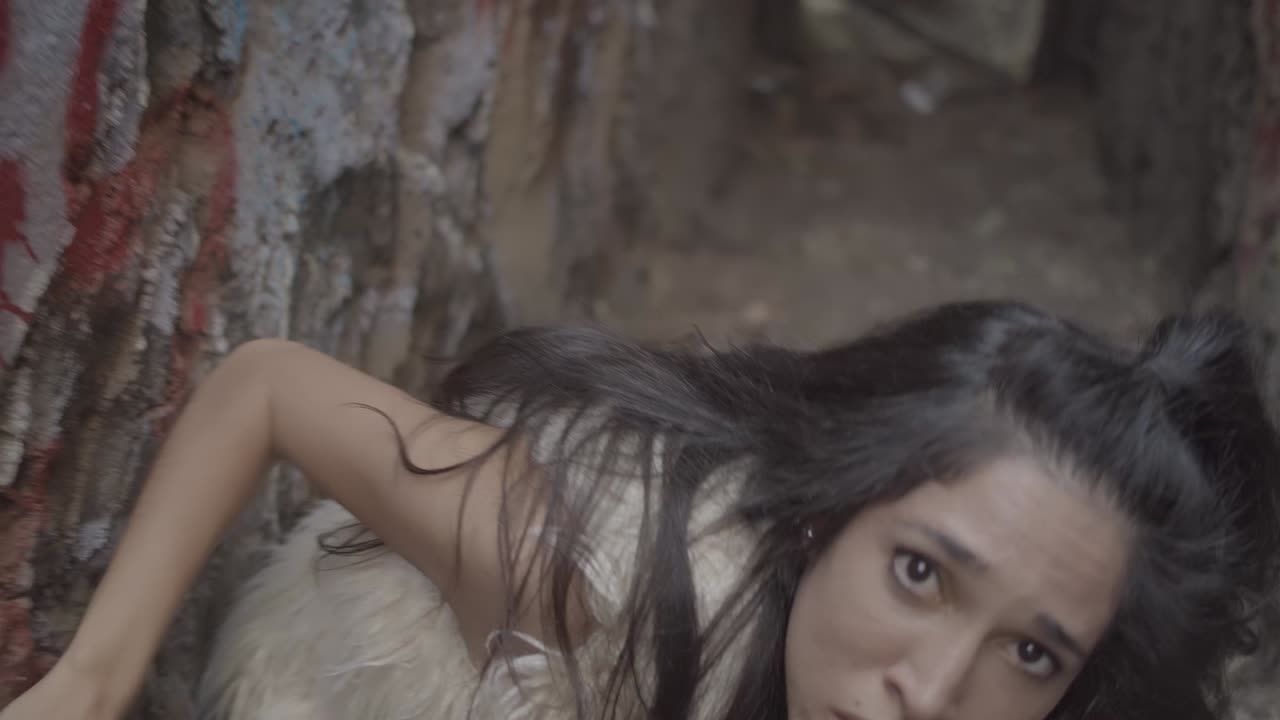 Artsy shot of a woman with long hair in an abandoned staircase doing a twisty interpretive dance