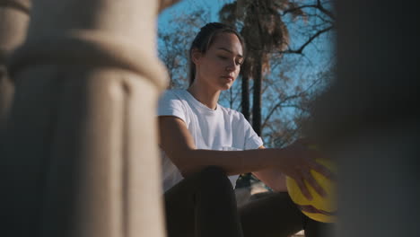 Sportliche-Frau-Mit-Fußball-In-Der-Hand-Sitzt-Auf-Der-Treppe-Im-Freien.