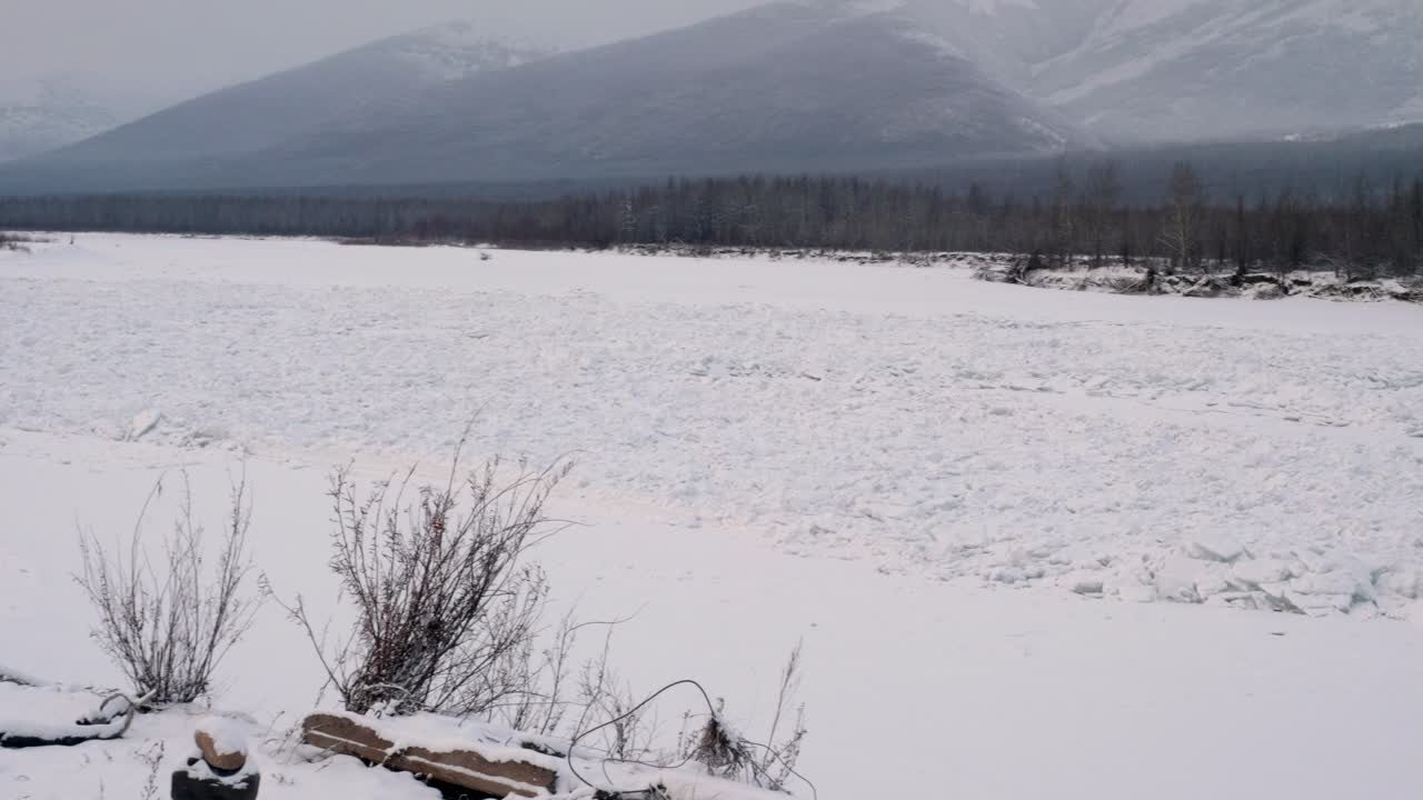 Quiet winter landscape featuring a snow-covered field and distant mountains. Peaceful, serene wilderness scene with soft, diffused light