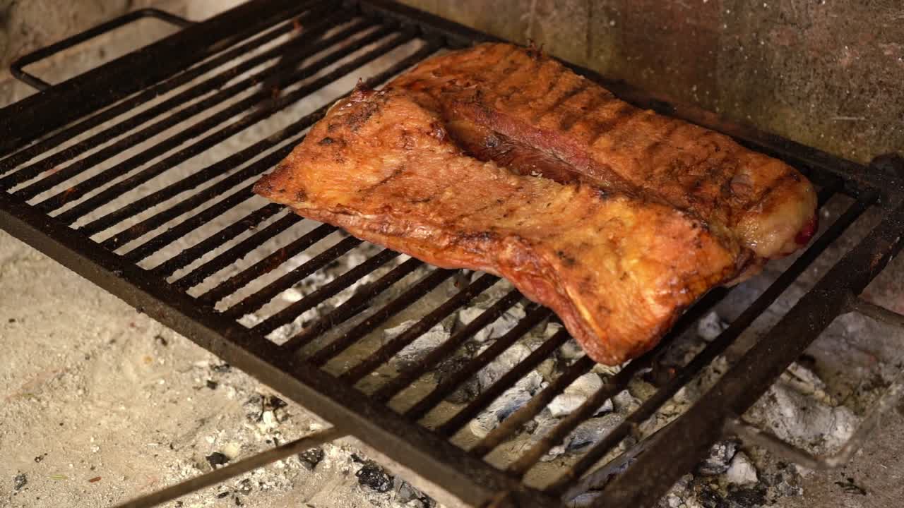 Añadiendo brasas calientes a la parrilla para cocinar un asado argentino