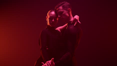 elegant dancers posing camera dark studio. elegant dance couple holding hands.