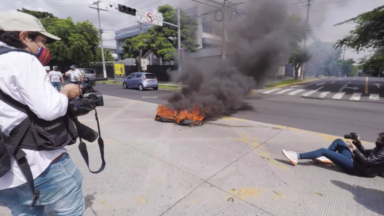 Photojournalists capturing tires on fire during protest march against the use of Bitcoin and President Nayib Bukele