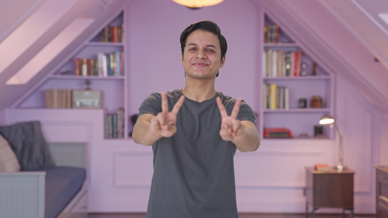 hombre indio feliz mostrando el signo de la victoria