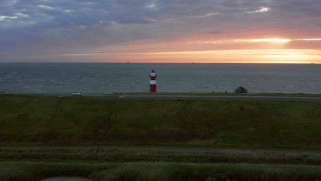 the lighthouse of westkapelle during a bright orange sunset, with a lot of wind