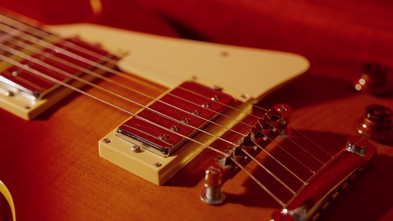 Gitara elektryczna typu sunburst spoczywa w wyściełanym futerale, ujęcie w zwolnionym tempie