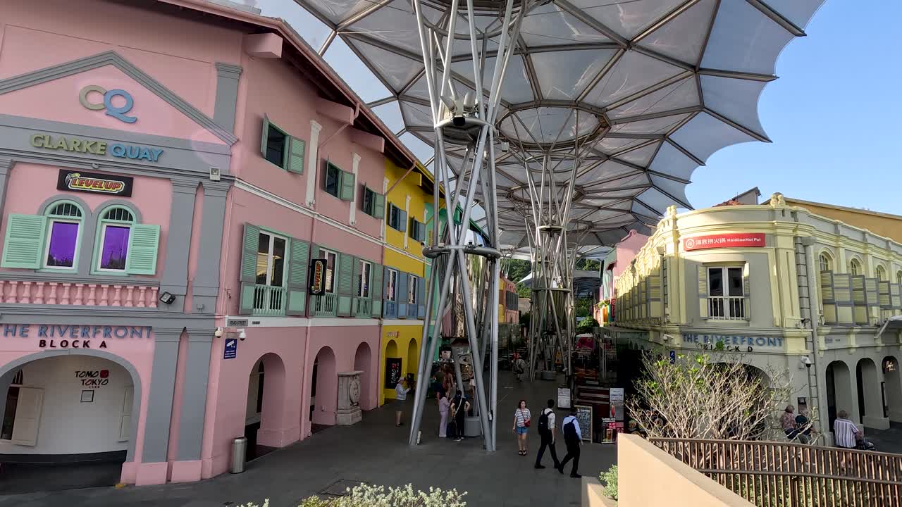 Camera pans from colorful Clarke Quay buildings to modern skyscrapers under bright daylight in Singapore