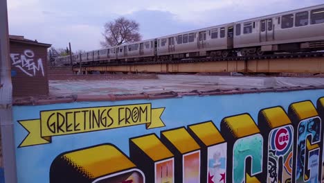 una antena sobre un letrero del centro de chicago pintado en una pared mientras pasa un tren el 1