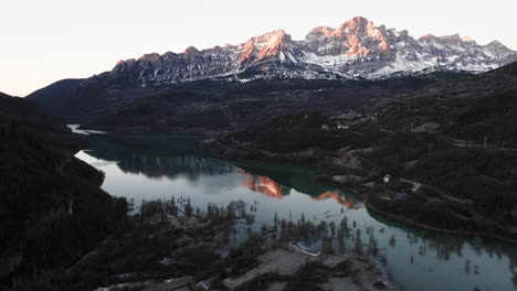 sunrise over snowy mountain peaks and a calm alpine lake