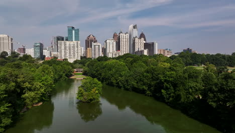 Aerial-panoramic-view-of-midtown-behind-park-with-trees-and-lake