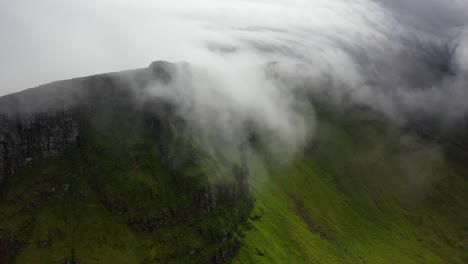 Aerial-flight-through-atmospheric-cloudy-mountain-peak-in-Faroe-Islands