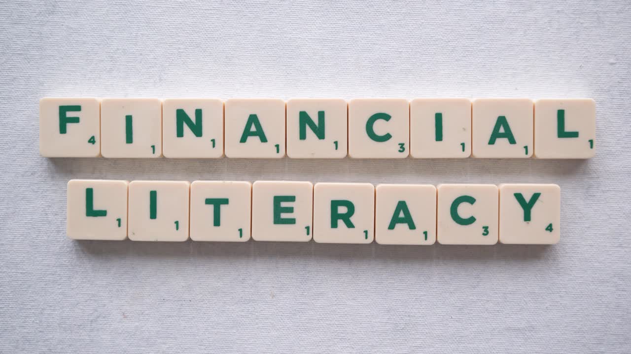 Hand forming phrase "financial literacy" with green letters