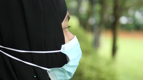 thoughtful muslim woman with flu mask looking away