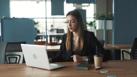 stern young woman is talking over a video call through her laptop, gesticulating and banging on the table