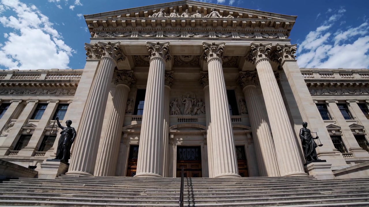 Vista dal basso dell'imponente ingresso di un tribunale con statua della Giustizia