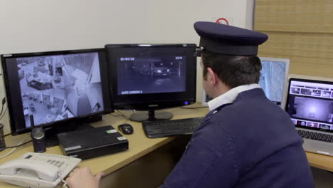 a security guard watches the surveillance cctv monitor screens in the office