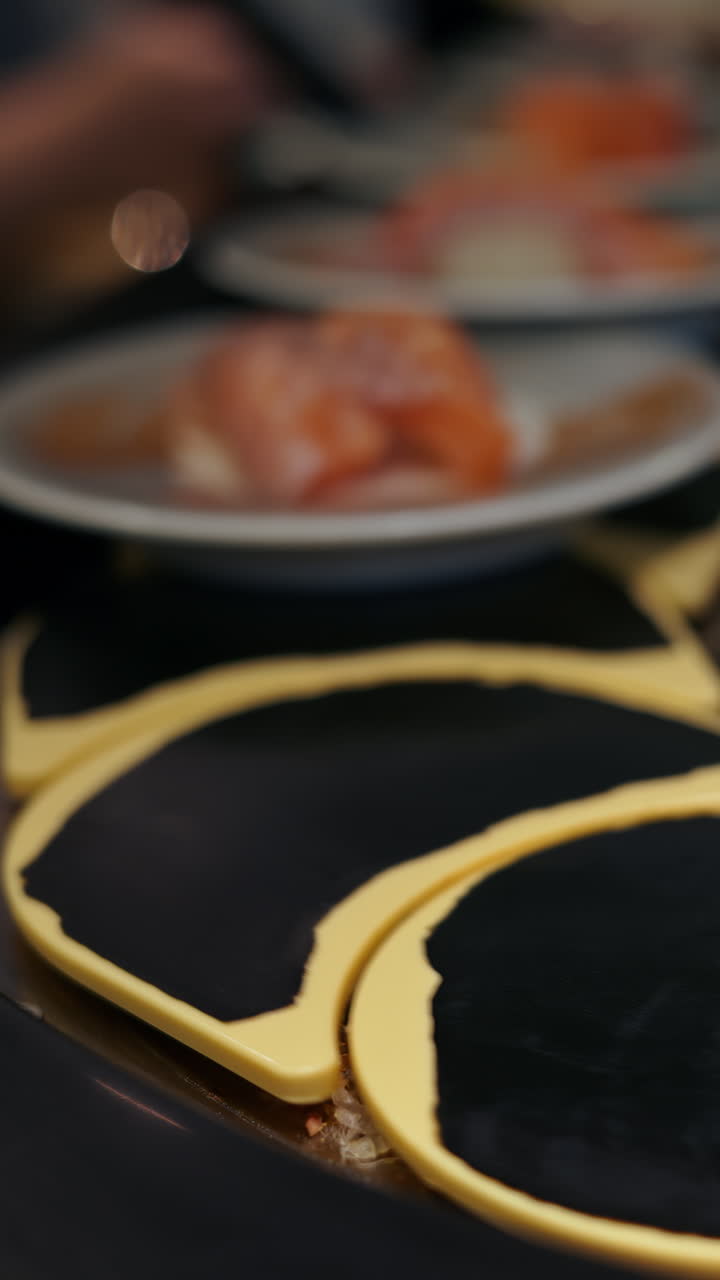 Close up of plates with sushi placed on a rotating conveyor belt moving through the restaurant. Vertical