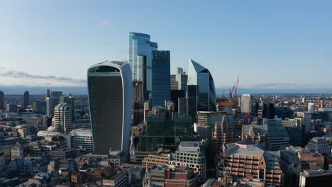 Slide-and-pan-footage-of-group-of-modern-skyscrapers-in-City-financial-hub.-Tall-office-buildings-lit-by-late-afternoon-sunlight.-London,-UK