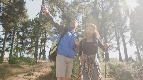 Happy-african-american-couple-hiking-with-trekking-poles-in-forest,-slow-motion