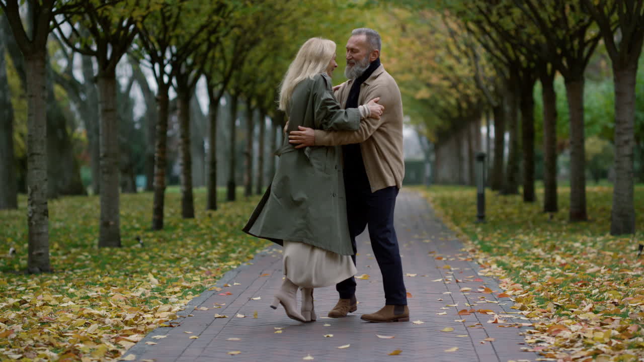 una pareja feliz bailando en el parque de otoño.
