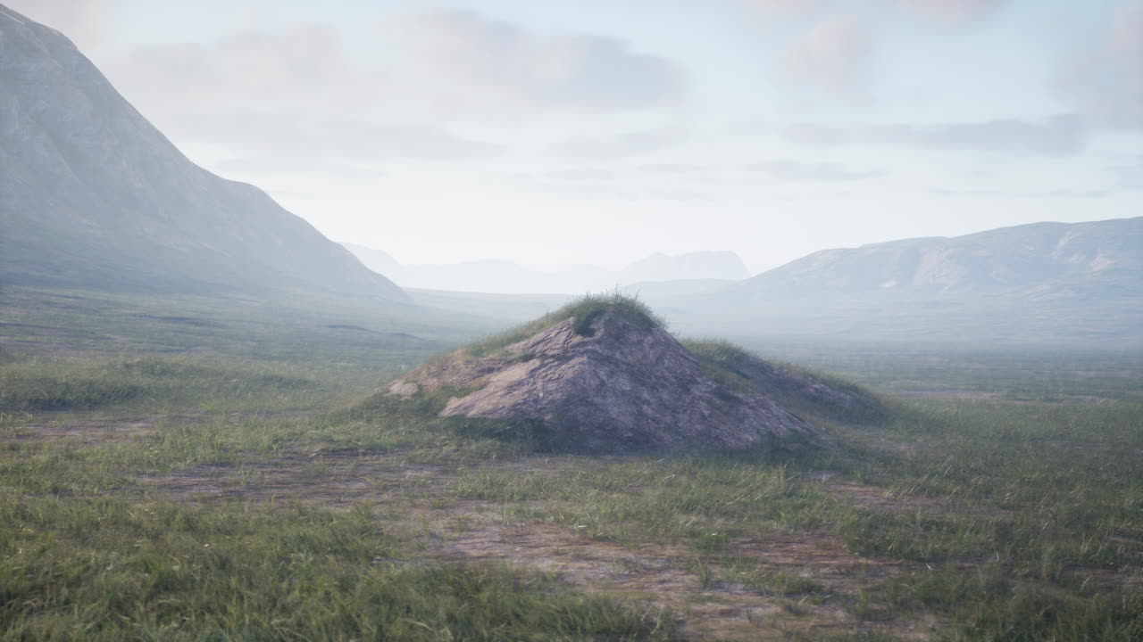 paisaje montañoso brumoso con campo de hierba