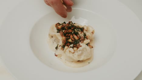 plating dumplings in yogurt cream dish, adding pine tree seeds