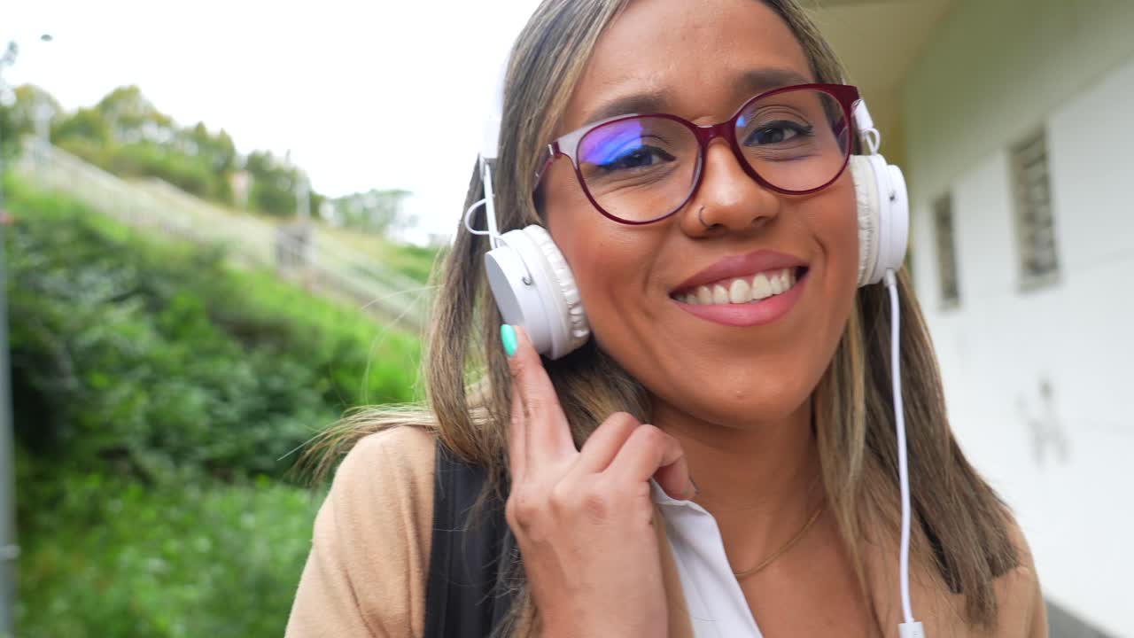 A woman wearing headphones and glasses on the street