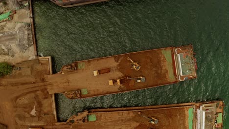 diggers on a barge removing natural materials from the back of a truck and placing it on the barge at a nickel mine in taganito, philippines