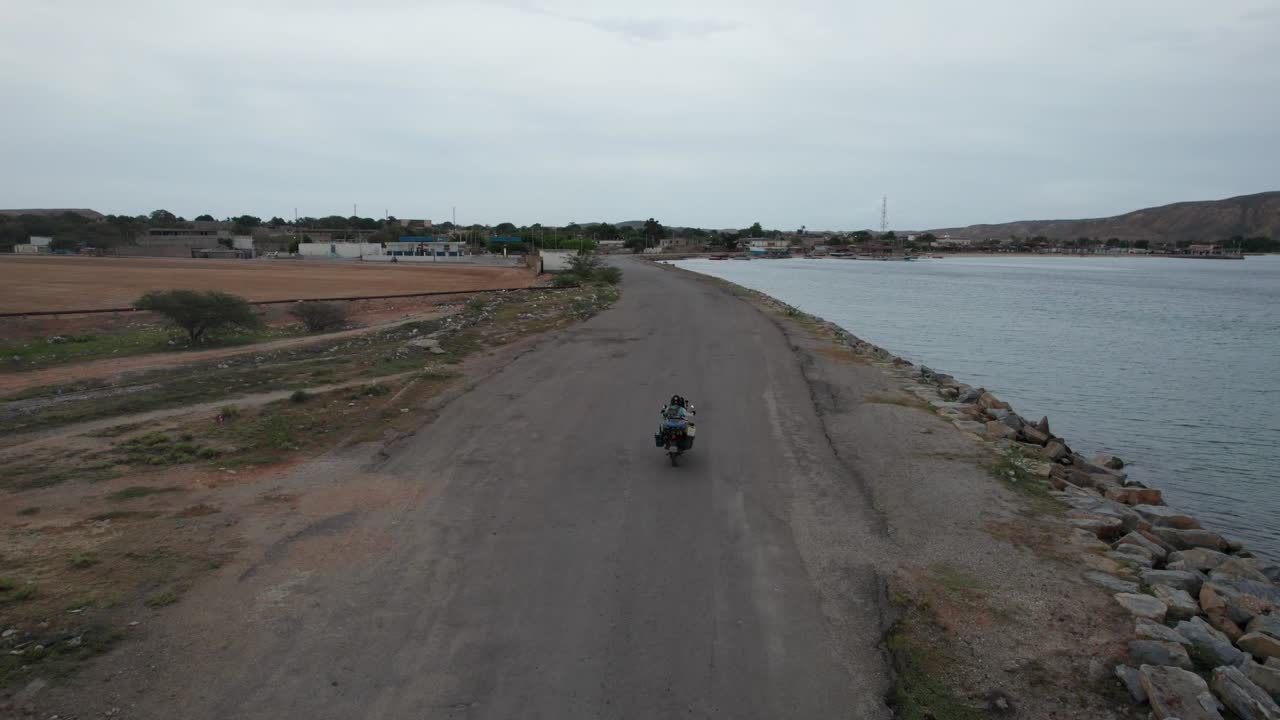 Aerial view of solo motorcycle rider on remote coastal road in Venezuela