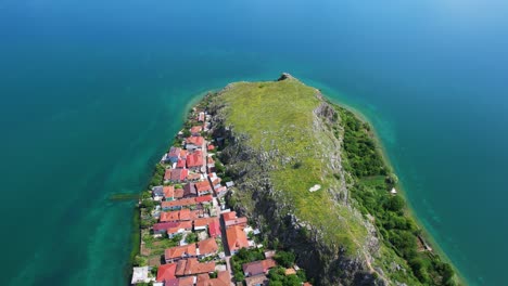 Emerald-Green-Hues-Adorning-the-Rocky-Peninsula-Edge-on-Village-of-Lin,-Beautiful-Shoreline-of-Pogradec-Lake